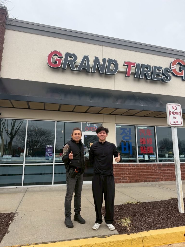 Father and son owners standing in front of the Grand Tires storefront in Duluth, Georgia